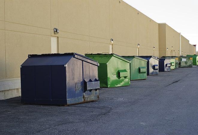 a forklift lifts a full dumpster from a work area in Bloomington